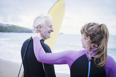 Father and daughter with surfboard on beach - CUF25965