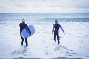 Vater und Tochter mit Surfbrettern gehen ins Meer - CUF25966