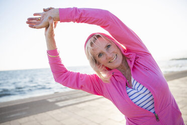 Senior woman stretching by beach - CUF26038