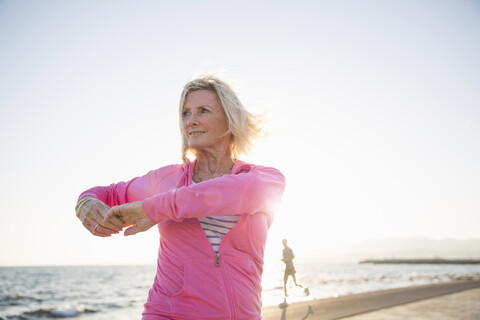 Ältere Frau beim Stretching am Strand, lizenzfreies Stockfoto