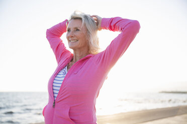 Senior woman stretching by beach - CUF26040