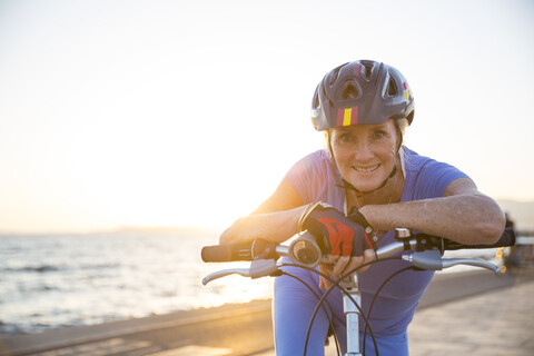 Ältere Frau auf dem Fahrrad am Strand, lizenzfreies Stockfoto