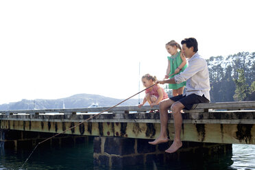 Mature man and daughter fishing from sea pier, New Zealand - CUF26048