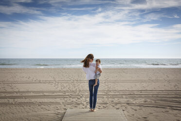 Rear view of mid adult woman carrying toddler daughter on beach, Castelldefels, Catalonia, Spain - CUF26058