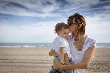 Mid adult woman kissing toddler daughter on beach, Castelldefels, Catalonia, Spain - CUF26062