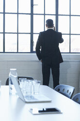 Rückansicht eines Geschäftsmannes, der in einem Konferenzraum mit seinem Smartphone chattet - CUF26154