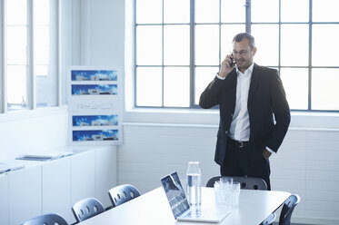 Business man chatting on smartphone in conference room - CUF26155