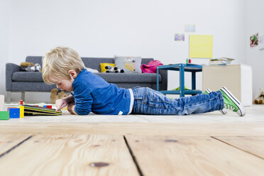 Junge spielt mit digitalem Tablet auf Holzboden - CUF26193