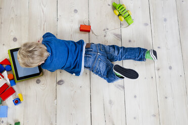 Boy playing with digital tablet on wooden floor - CUF26194