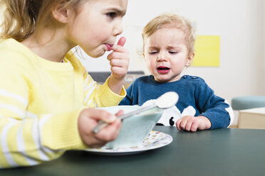 Sister testing temperature before feeding baby brother - CUF26208