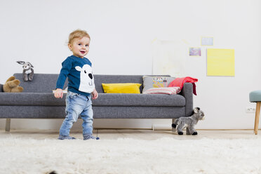 Boy standing beside sofa at home - CUF26231
