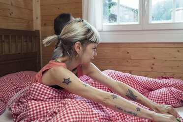 Two women looking through window from log cabin bed, Tyrol, Austria - CUF26260