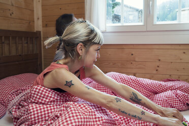 Zwei Frauen schauen durch ein Fenster aus einem Blockhausbett, Tirol, Österreich - CUF26260