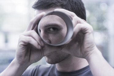 Engineer in engineering plant looking through plastic tube - CUF26287