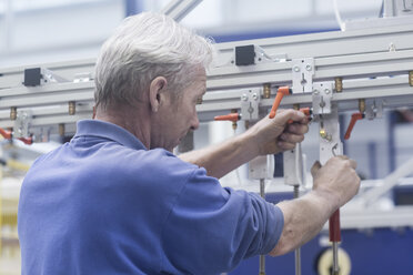 Ingenieur bei der Arbeit an einer Metallschiene in einer Maschinenfabrik - CUF26300