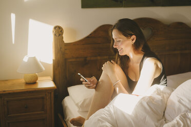 Woman using mobile phone in bed - CUF26329