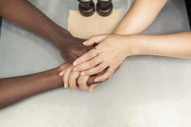 Overhead view of couple holding hands at sidewalk cafe table - CUF26337