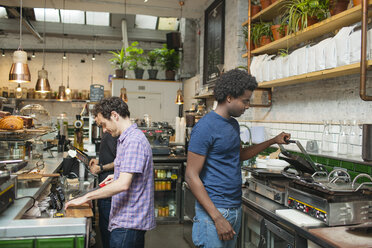 Zwei Kellner bereiten in der Küche eines Cafés Essen zu - CUF26348