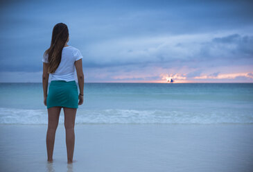 Rückansicht einer jungen Frau, die bei Sonnenuntergang aufs Meer hinausschaut, Insel Boracay, Visayas, Philippinen - CUF26512