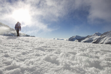 Tiefblick auf männlichen Wanderer in verschneiter Landschaft, Jungfrauchjoch, Grindelwald, Schweiz - CUF26539