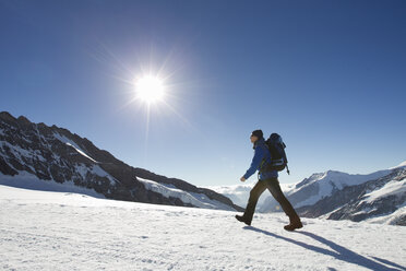 Mann wandert durch schneebedeckte Berglandschaft, Jungfrauchjoch, Grindelwald, Schweiz - CUF26540