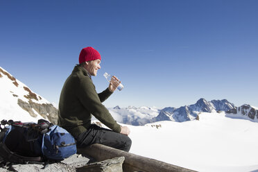 Männlicher Wanderer trinkt Wasser auf der Aussichtsplattform, Jungfrauchjoch, Grindelwald, Schweiz - CUF26544