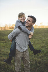Boy getting piggy back from father in field - CUF26601