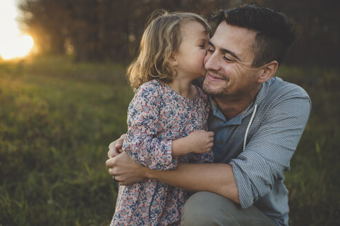 Mädchen küsst Vater auf die Wange im Feld - CUF26630