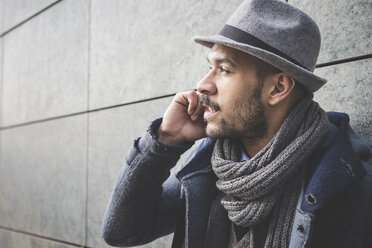 Close up of businessman leaning against wall talking on smartphone - CUF26655