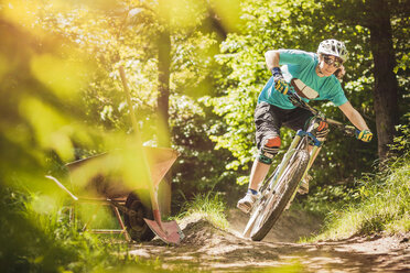 Young female mountain biker riding forest track - CUF26665