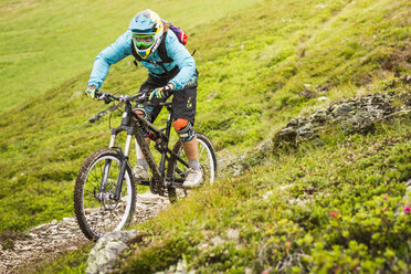 Junge Mountainbikerin fährt auf einer Bergstrecke - CUF26669