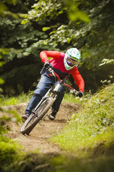 Junge Frau beim Downhill-Mountainbiking im Wald - CUF26673