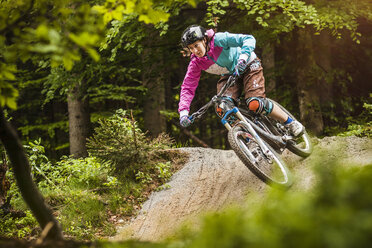 Young female mountain biker jumping on forest track - CUF26679