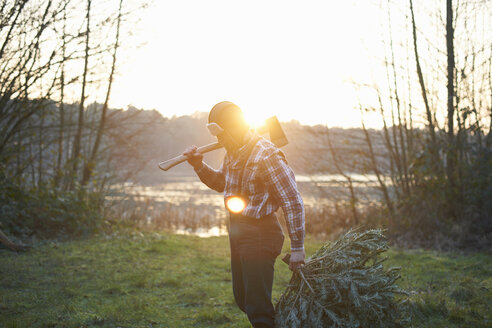 Woodsman with axe over his shoulder in forest at sunset - CUF26681