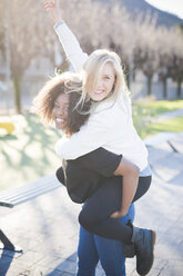 Two female friends giving piggy backs in park - CUF26754