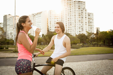 Junges Paar unterhält sich, während es sich auf das Radfahren im Park vorbereitet - CUF26756