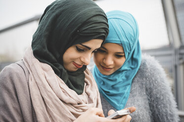 Zwei junge Freundinnen lesen Smartphone-Texte auf einem Parkweg - CUF26767