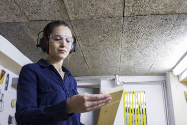 Junge Schreinerin prüft Holz in der Werkstatt - CUF26921