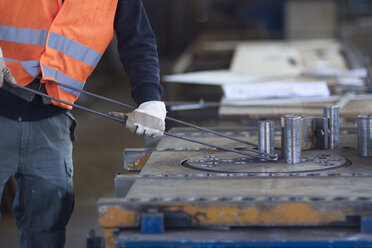 Fabrikarbeiter beim Biegen von Metallstäben in einer Fabrik für Betonbewehrung - CUF27004