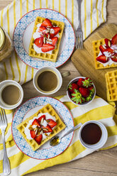 Zwei Teller mit Waffeln, garniert mit Erdbeeren, griechischem Joghurt und Mandeln auf dem Frühstückstisch - GIOF03958
