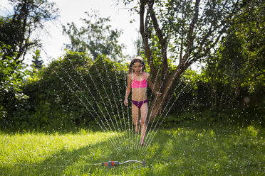 Little girl having fun with lawn sprinkler in the garden - LVF07054