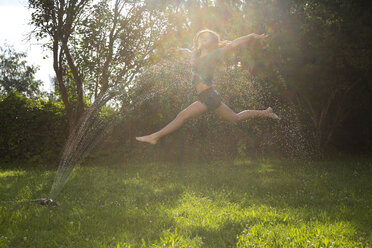 Ein Mädchen springt im Garten in die Luft - LVF07059