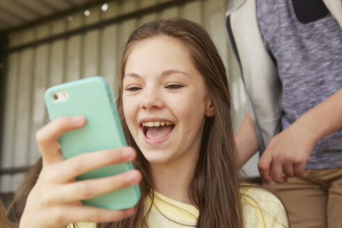Mädchen lachen über Smartphone im Schutzraum - CUF27141