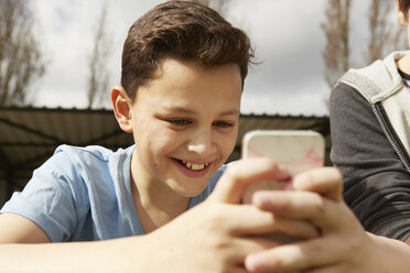 Lächelnder Junge liest Smartphone-SMS - CUF27145