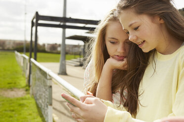 Two girls reading smartphone text message - CUF27146