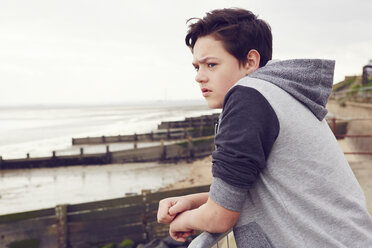 Unhappy teenage boy looking out from railings, Southend on Sea, Essex, UK - CUF27153