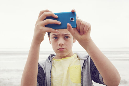 Jugendlicher, der ein Smartphone-Selfie am Meer macht, Southend on Sea, Essex, Großbritannien - CUF27154