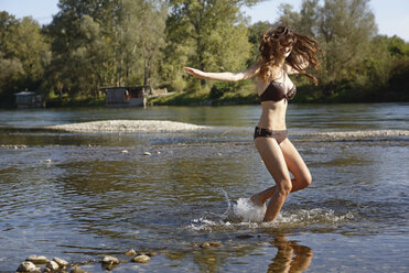 Junge Frau im Bikini plantscht und spielt im Fluss - CUF27158