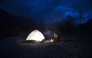 Man by campfire and tent at night - CUF27186