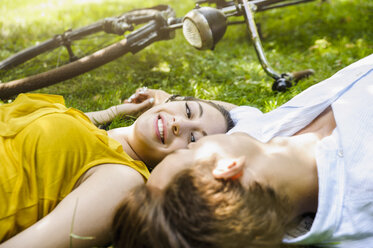 Young couple lying on grass holding hands - CUF27222